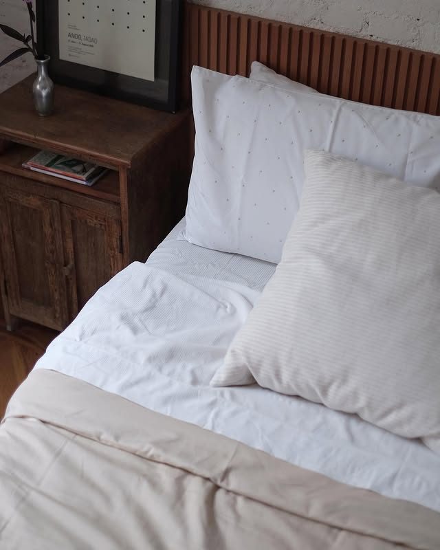 Cama arrumada com criado-mudo de madeira